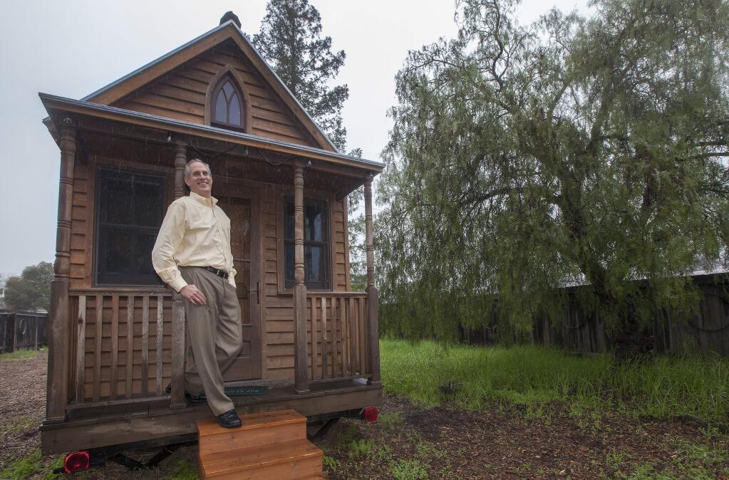 Tiny house on the prairie: Steve Weissmann stretches out on the porch of one of the first tiny houses ever built back in 1999, and which has been retired to the back garden of his office on Broadway and West MacArthur. (Photos by Robbi Pengelly/Index-Tribune)