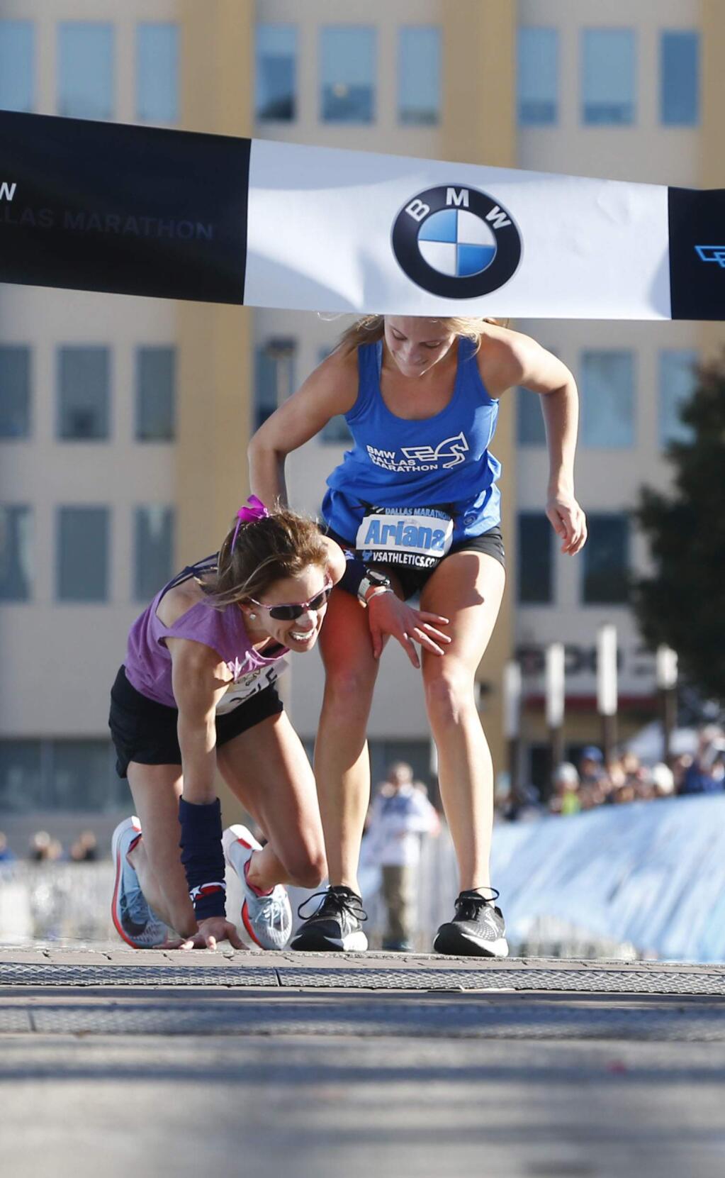 In this Sunday, Dec. 10, 2017, photo, Ariana Luterman, 17, right, helps Chandler Self at the finish line during the BMW Dallas Marathon in Dallas. (Nathan Hunsinger/The Dallas Morning News via AP)