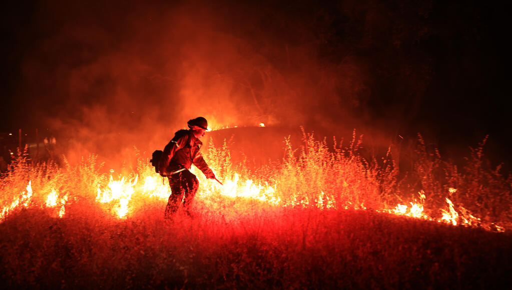 Joe Stewart with the Northern Sonoma County Fire Protection District lights a backfire to burn off brush in advance of the Wilson Fire along Geysers Road near Geyserville, Monday, July 4, 2022. (Kent Porter / The Press Democrat)