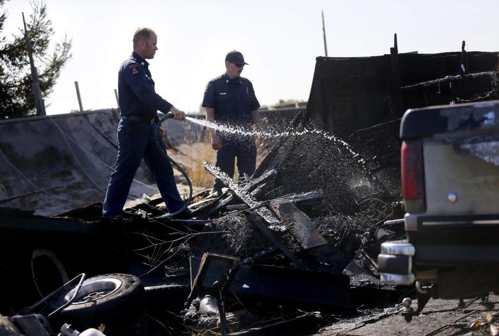 Rancho Adobe Fire engineer Mike Porter, left, and firefighter Morgan De Jong extinguish the remains of a fire on Snyder Lane near Rohnert Park , on Monday, October 5, 2015. (BETH SCHLANKER/ The Press Democrat)