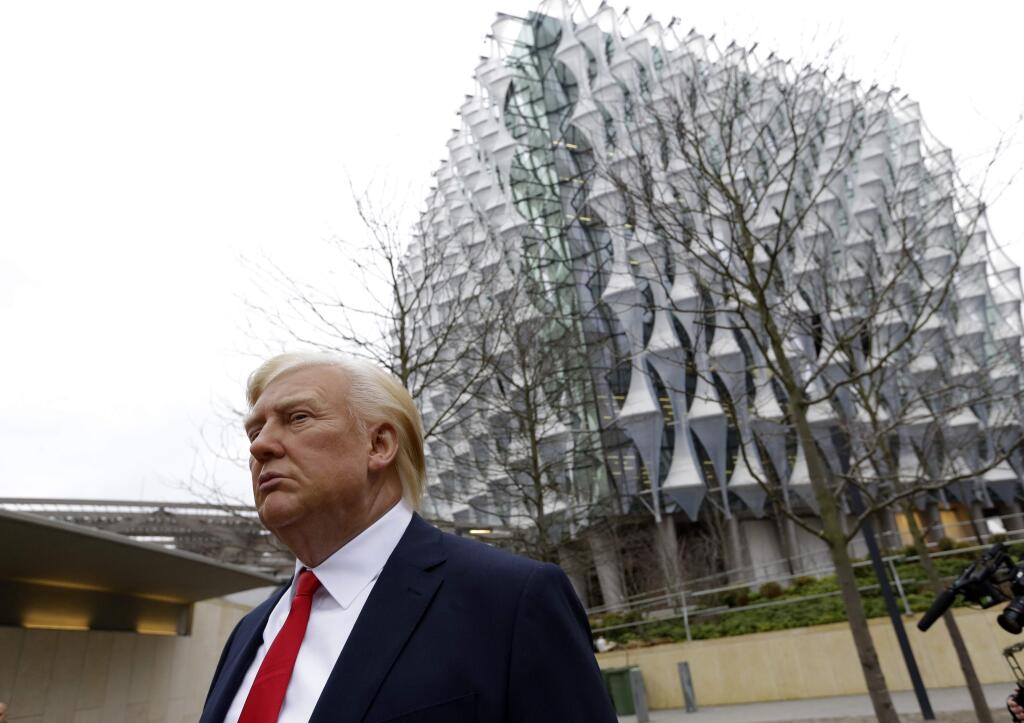 The Madame Tussauds wax figure of US President Donald Trump is seen outside the new US Embassy in Nine Elms in London, Friday, Jan. 12, 2018. President Donald Trump says he canceled upcoming trip to London because he doesn't like the choice of a new embassy. Some British lawmakers have questioned whether Trump would be welcome in London after some of his earlier comments. (AP Photo/Alastair Grant)