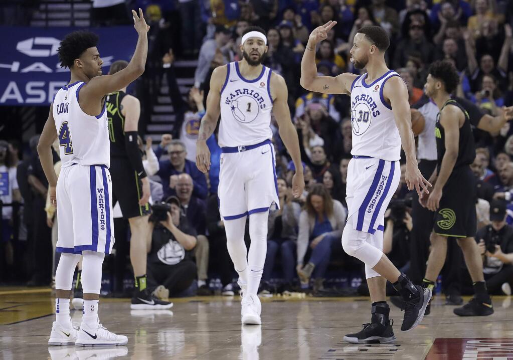 Golden State Warriors guard Stephen Curry, right, celebrates after scoring with guard Quinn Cook, left, and center JaVale McGee during the second half against the Atlanta Hawks in Oakland, Friday, March 23, 2018. (AP Photo/Jeff Chiu)