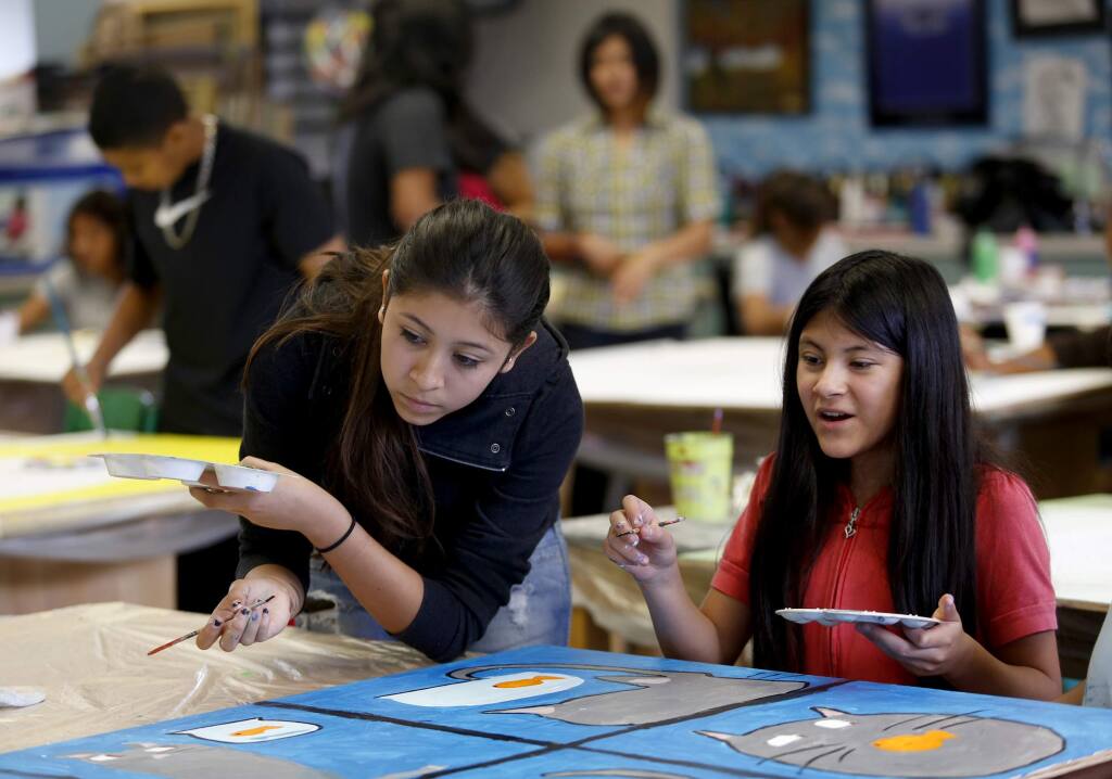 Stacey Santiago, 16, left, and her sister, Amy, 12, help brother Kevin, 8, with his painting during a session of the One City Arts program at Cook Middle School in Santa Rosa, on Wednesday, July 23, 2014. (Beth Schlanker / The Press Democrat)