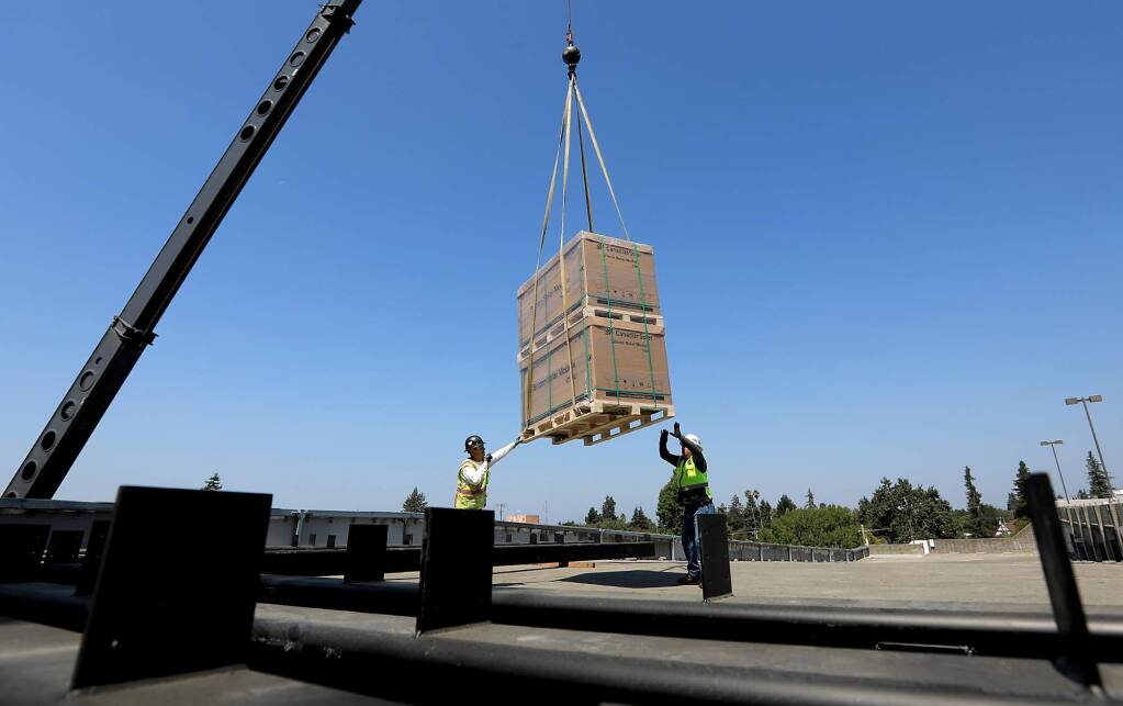 Hardware for the installation of solar panels are lifted to the top of the Fifth Street garage in Santa Rosa, Tuesday August 15, 2017. (Kent Porter / The Press Democrat) 2017