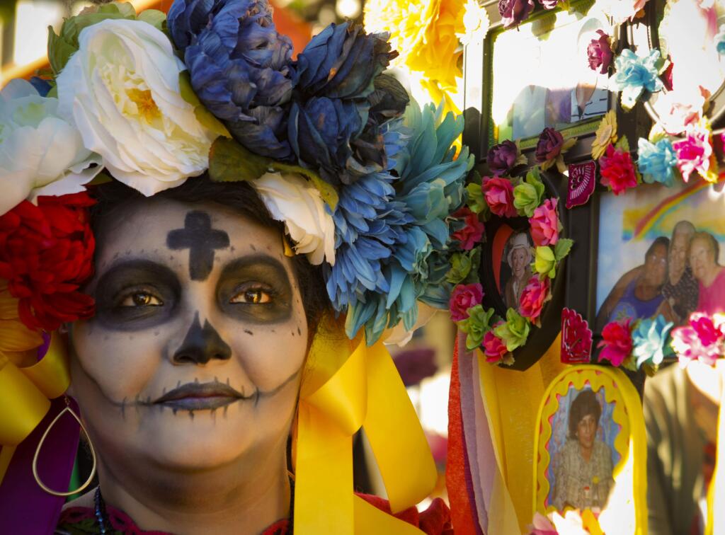 Petaluma, CA. Saturday, October 28, 2017._The Die de los Muertos celebration, a Mexican tradition begins with a parade in downtown Petaluma and ends with festive dances to honor the lives of loved ones lost. Karla Rodriguez of San Francisco carried photos of her family and friends during the procession. (CRISSY PASCUAL/ARGUS-COURIER STAFF)