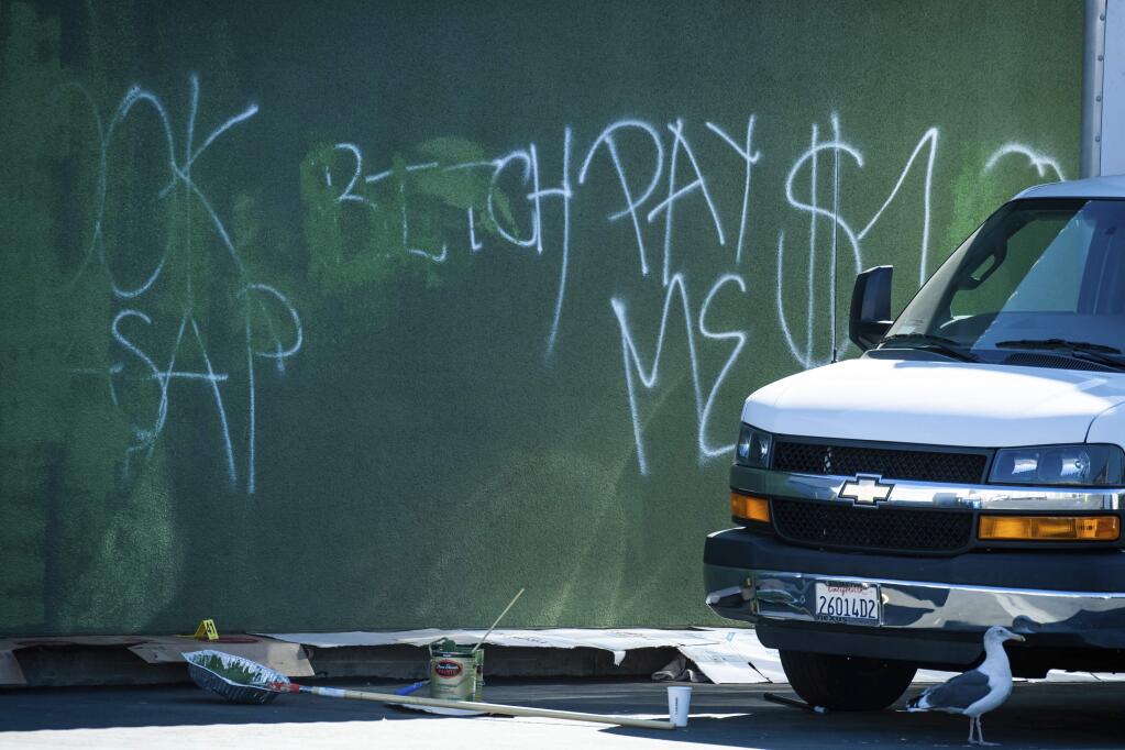 EDS NOTE: OBSCENITY - This Oct. 28, 2019 photo shows partially erased graffiti found on the side of Royal Fresh Market in North Hollywood. Employees were attempting to paint over the graffiti when the owner got into a shootout with suspected Armenian gang members who were trying to extort his business according to the LAPD. One suspect who was shot was taken into custody while others were still at large. (Sarah Reingewirtz/The Orange County Register via AP)