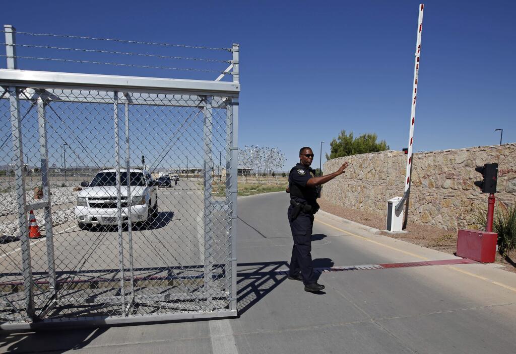 FILE - In this June 21, 2018, file photo, an agent with the Department of Homeland Security controls access to a holding facility for immigrant children in Tornillo, Texas. The Trump administration is reversing a policy that required fingerprinting for all adults living in a household where a migrant child would live. Parents and other sponsors have said the fingerprinting rule had slowed placement of children in homes, in part because some members of the household were afraid to be fingerprinted. (AP Photo/Andres Leighton, File)