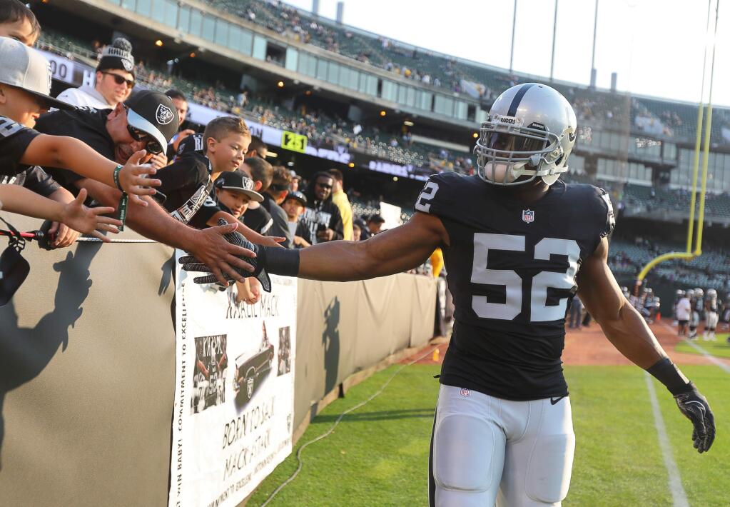 Oakland Raiders defensive end Khalil Mack greets young fans during pregame warmups in Oakland on Saturday, Aug. 19, 2017. (Christopher Chung / The Press Democrat)