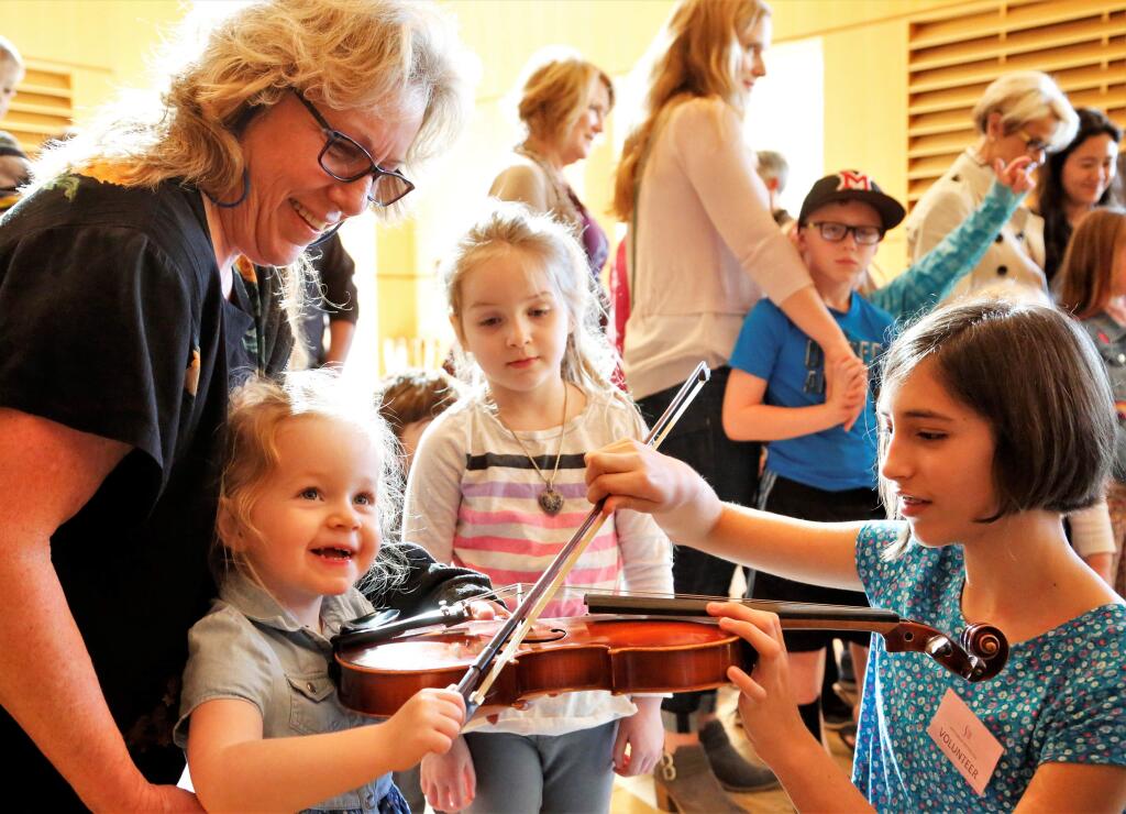 Pippin Forrest (right), taught Parker Beehler how to hold the violin as her sister Peyton (center) and grandmother Luann Nelson look on while they visited the instrument petting zoo prior to the concert. The Santa Rosa Symphony presented 'Green Eggs and Ham' and 'Tubby the Tuba' as part of the Finley Foundation Family Concert Series at Weill Hall, Sonoma State University on Sunday, Jan. 28, 2018. (Will Bucquoy/For the Press Democrat)
