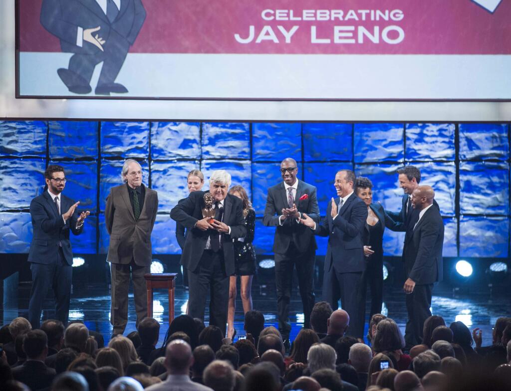 Mark Twain Prize honoree Jay Leno holds the prize as he is joined by, from left, Al Madrigal, Robert Klein, Chelsea Handler, Kristen Chenoweth (behind Leno), J.B. Smoove, Jerry Seinfeld, Wanda Sykes, Seth Meyers, and Kevin Eubanks speaks at the Kennedy Center for the Performing Arts for the Mark Twain Prize for American Humor on Sunday, Oct. 19, 2014, in Washington. (AP Photo/Kevin Wolf)
