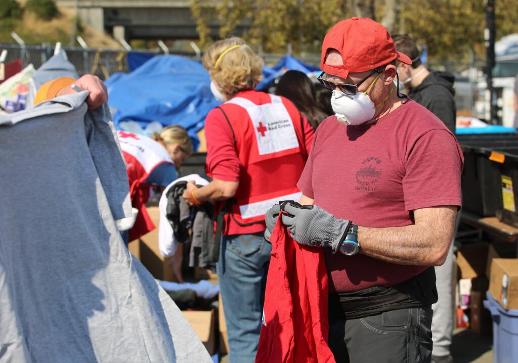 A volunteer sorts through donated items at the Sonoma County Fairgrounds. The Sonoma County Fairgrounds has been converted into a city that houses evacuees, an animal shelter, the command center for Cal-Fire, a media center, temporary home to hundreds of fire fighters and their fire fighting equipment and so much more. Sunday, Oct. 15, 2017. (Will Bucquoy / For The Press Democrat)