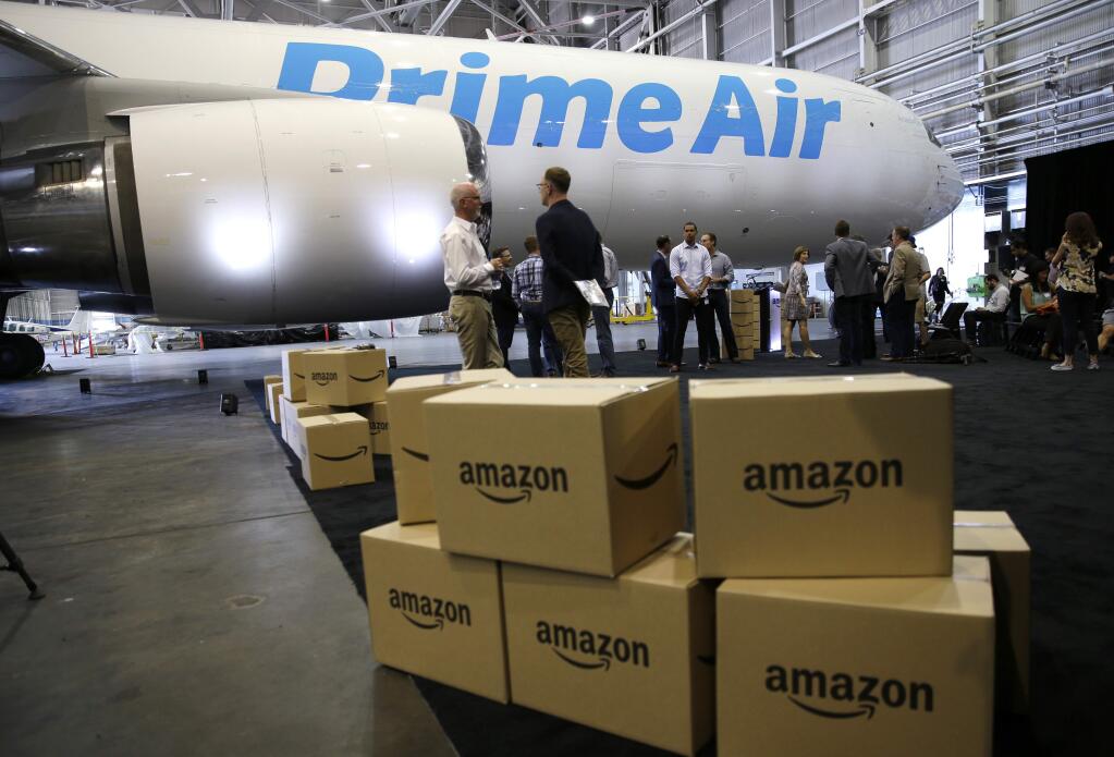 FILE - In this Thursday, Aug. 4, 2016, file photo, Amazon.com boxes are shown stacked near a Boeing 767 Amazon 'Prime Air' cargo plane on display in a Boeing hangar in Seattle. With Christmas 2017 on a Monday, most retailers have one less day to get packages delivered on time. Retailers have been trying to speed up delivery as they try to replicate the service offered by Amazon. (AP Photo/Ted S. Warren, File)