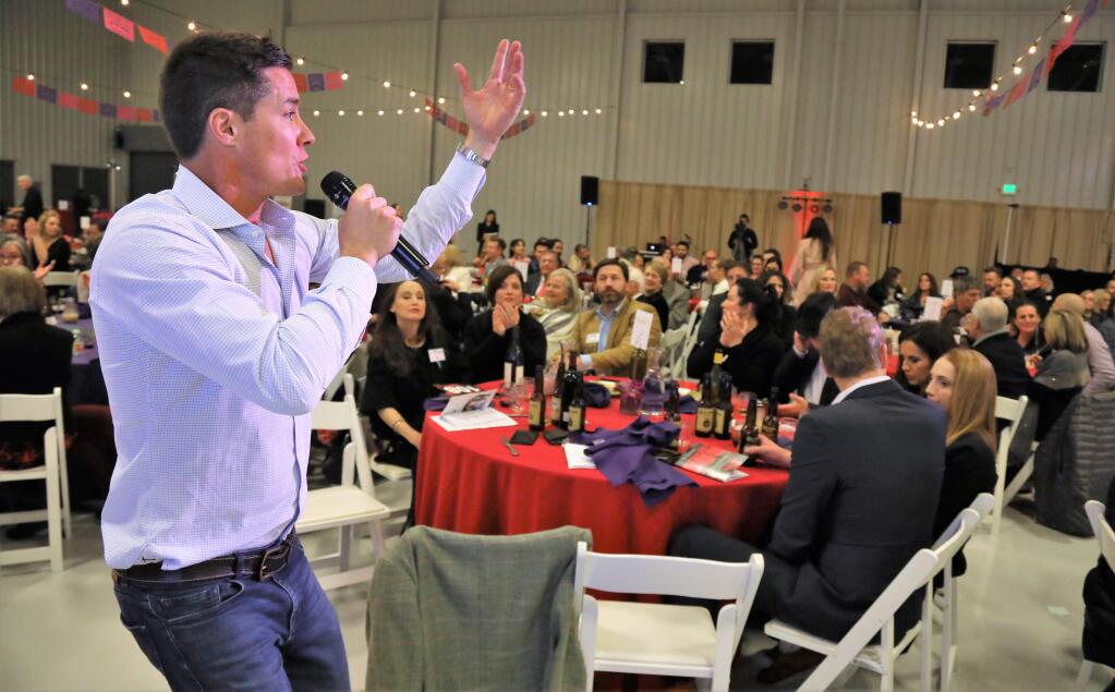 Celebrity auctioneer, famous from 'The Bachelor', Andrew Firestone takes bids from guests at the Healthcare Foundation Noche De Amor event at the Sonoma Jet Center in Santa Rosa, Saturday February 9th, 2019. (WILL BUCQUOY/For the PD)