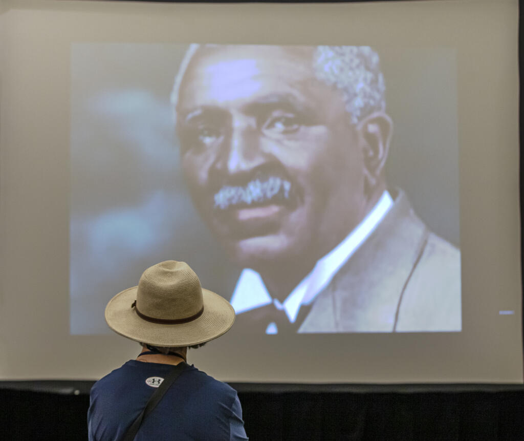 A visitor to The True Black History Museum pauses to watch a video about George Washington Carver while visiting the traveling exhibit at the Sonoma State University Student Center in Rohnert Park, Thursday, Feb. 8, 2024. (Chad Surmick / The Press Democrat)