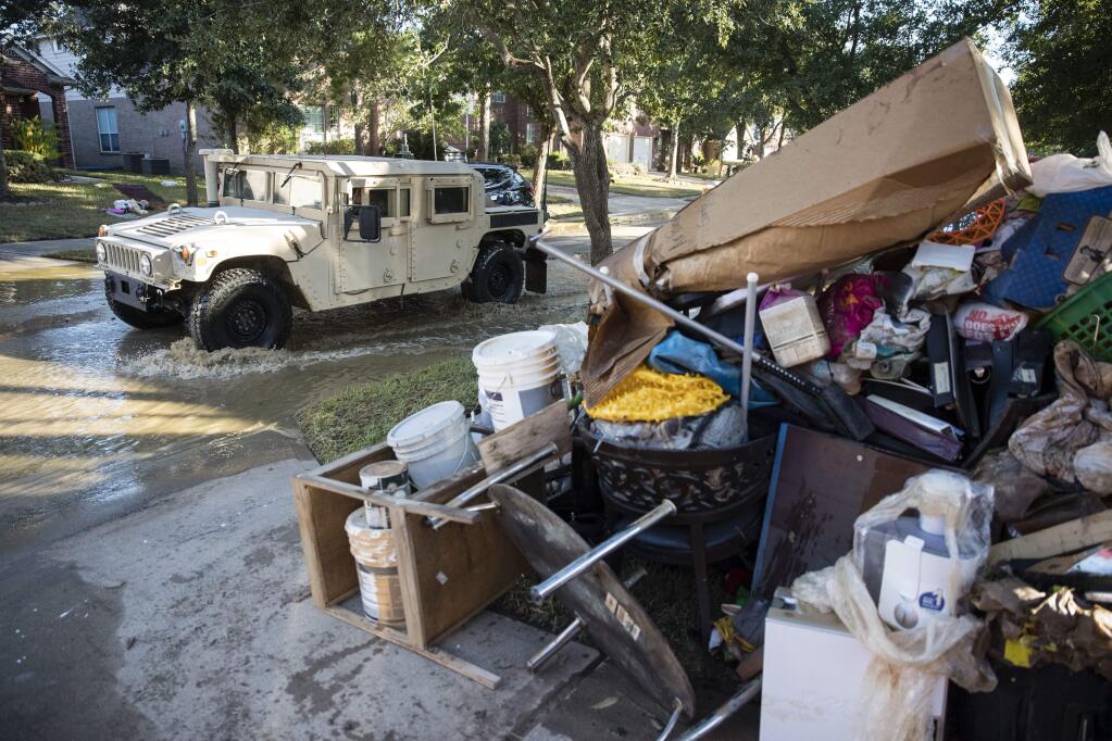 A military vehicle pass flood damaged belongings piled on a homeowners front lawn in the aftermath of Hurricane Harvey on Thursday, Sept. 7, 2017, at the Canyon Gate community in Katy, Texas. (AP Photo/Matt Rourke)