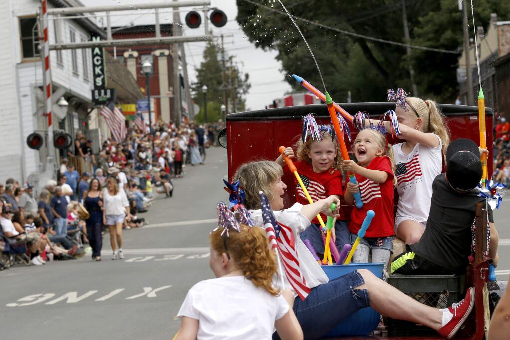 Gloria Pearson rides with her granddaughters Emma Joy Snyder, 4, Katelyn Gobbi, 4, and Alice Williams, 10, who shoot water onto the crowd from their truck during Penngrove's 39th annual 'Biggest Little Parade' on Sunday, July 5, 2015 in Penngrove, California . (BETH SCHLANKER/ The Press Democrat)