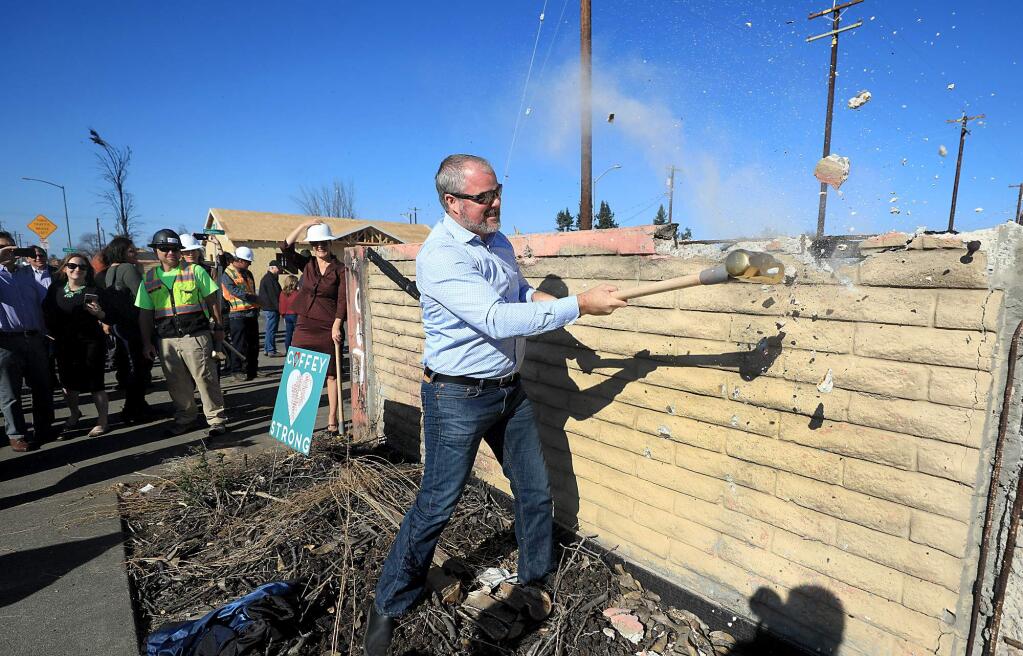 Sonoma County Supervisor James Gore breaks part of the fire-damaged Coffey Park wall on Thursday, Nov. 8, 2018, during the groundbreaking of the new wall along Hopper Avenue in Santa Rosa. (KENT PORTER/ PD)