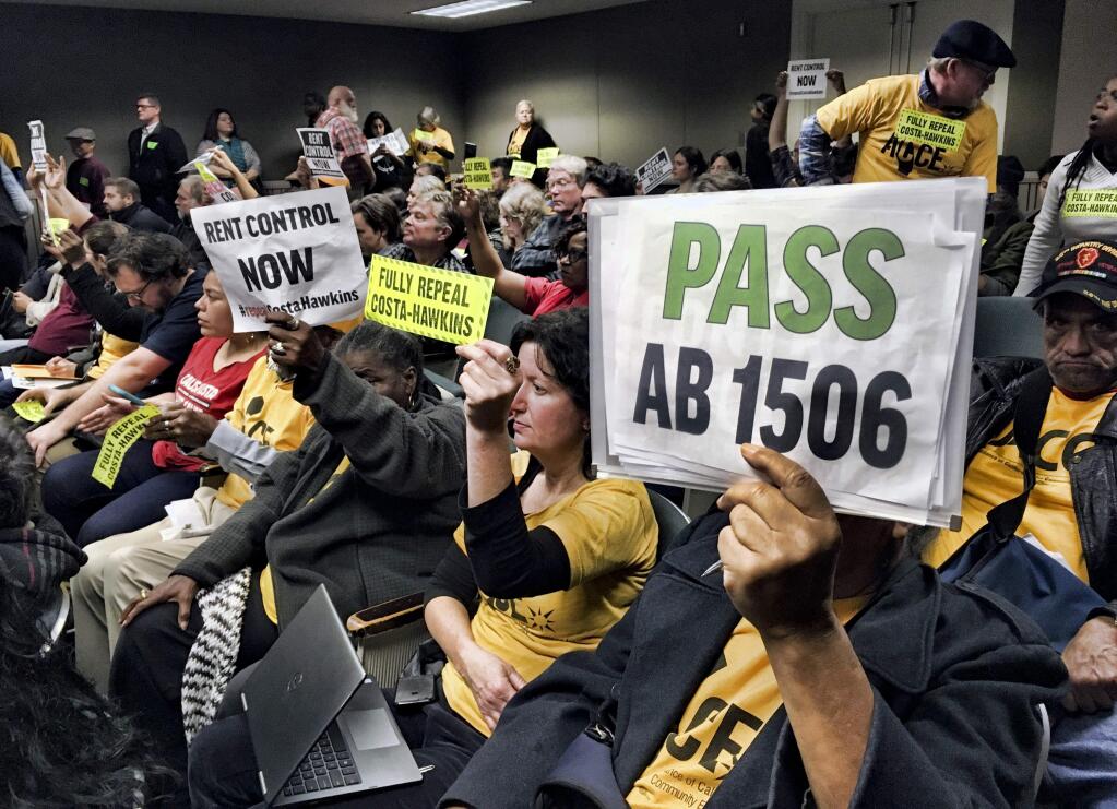 Voters hold signs demonstrating their support for legislation that would allow California communities to expand rent control policies during a legislative hearing Jan. 11 in Sacramento. The bill was defeated on a 3-2 vote. (KATHLEEN RONAYNE / Associated Press)