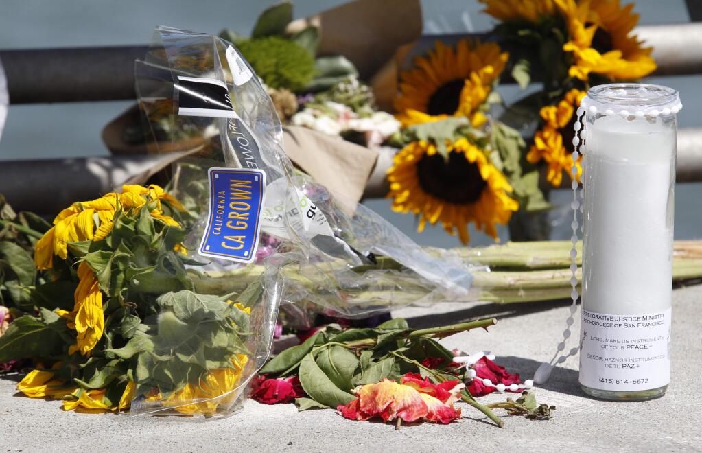 Flowers and a candle lay on the ground following a vigil for Kathryn Steinle, Monday, July 6, 2015, on Pier 14 in San Francisco. Steinle was gunned down while out for an evening stroll at Pier 14 with her father and a family friend on Wednesday, July 1. (AP Photo/Beck Diefenbach)