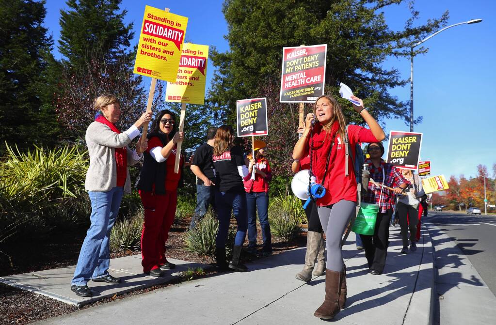 Marriage and family therapist Devon Maher, right, leads a chant with striking mental health professionals, along Santa Rosa Avenue, in front of the Kaiser Permanente Santa Rosa Medical Center on Tuesday, December 11, 2018. (Christopher Chung/ The Press Democrat)