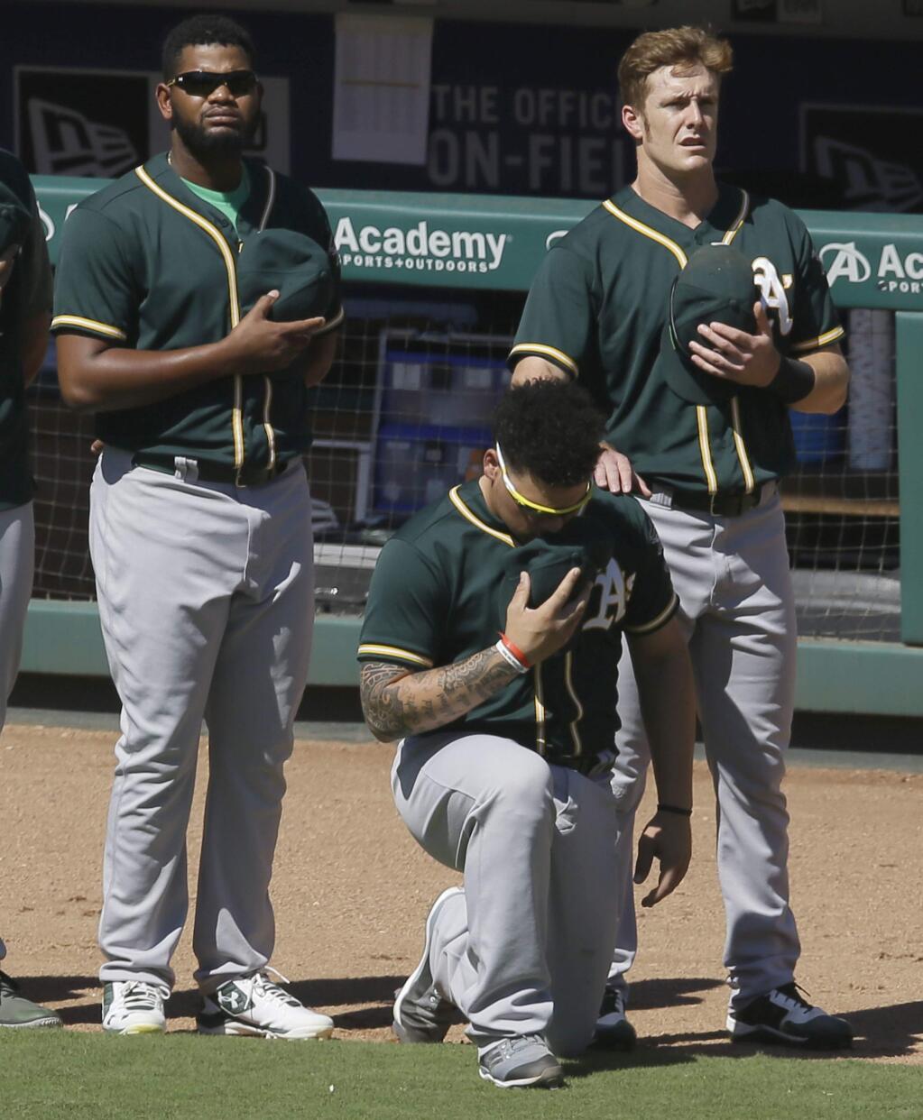 In this Sunday, Oct. 1, 2017 file photo, Oakland Athletics catcher Bruce Maxwell takes a knee during the national anthem next to teammates Mark Canha, right, and Raul Alcantara before a game against the Texas Rangers in Arlington, Texas. Oakland Athletics catcher Bruce Maxwell says he will no longer kneel for the national anthem as he did last season as a rookie, when he became the first major leaguer to do so following the lead of many NFL players. He spoke Tuesday, Feb. 13, 2018 as the A's pitchers and catchers reported to spring training. (AP Photo/LM Otero, File)