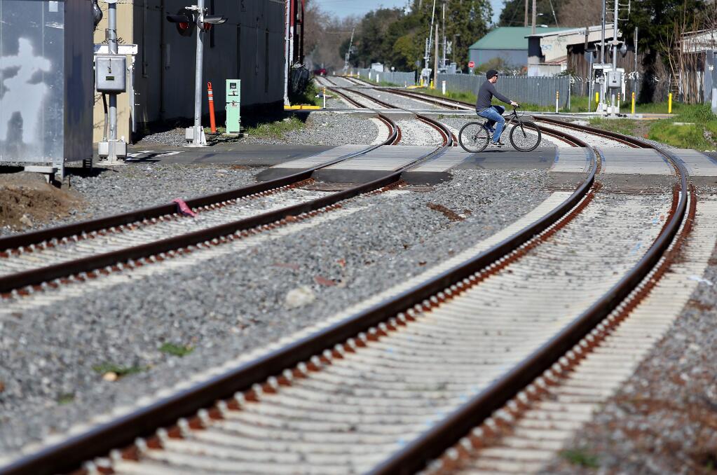 A cyclist rides across the railroad tracks at 6th Street in Santa Rosa on Wednesday, Feb. 25, 2015. (Christopher Chung / The Press Democrat)