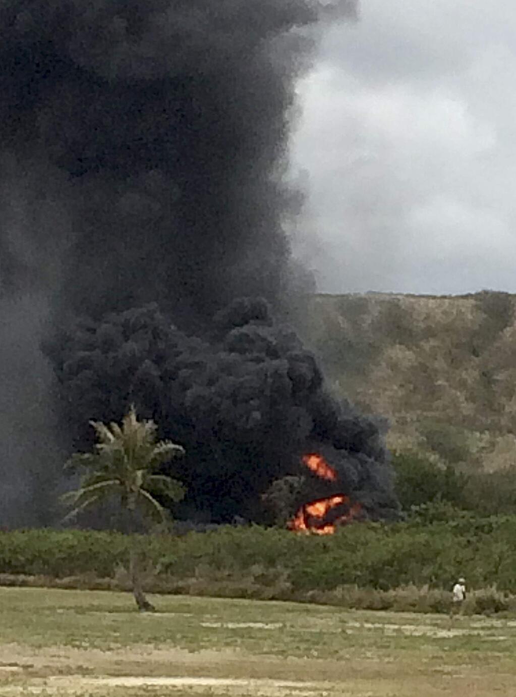 In this May 17, 2015 photo, smoke rises from a Marine Corps Osprey aircraft after making a hard landing near Bellows Air Force Station near Waimanalo, Hawaii. The fatal crash of the Marine Corps' new hybridized airplane-and-helicopter aircraft during a training exercise is renewing safety concerns about the machine. (Zane Dulin via AP)