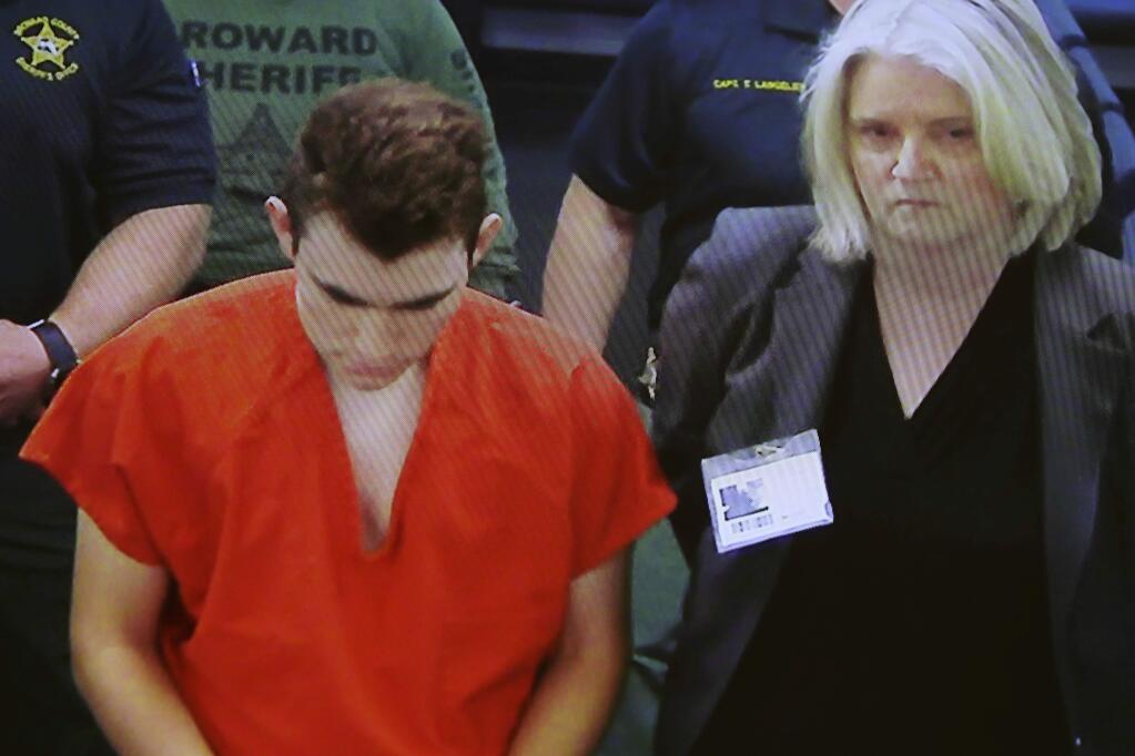 In this image taken from a video monitor, Nikolas Cruz, center, a former student accused of opening fire at Marjory Stoneman Douglas High School on Feb. 14, appears in magistrate court via video conference from jail on Friday, March 9, 2018, for his initial appearance on attempted murder charges that were added by the grand jury, in Fort Lauderdale, Fla. (Broward County Court/South Florida Sun-Sentinel via AP)