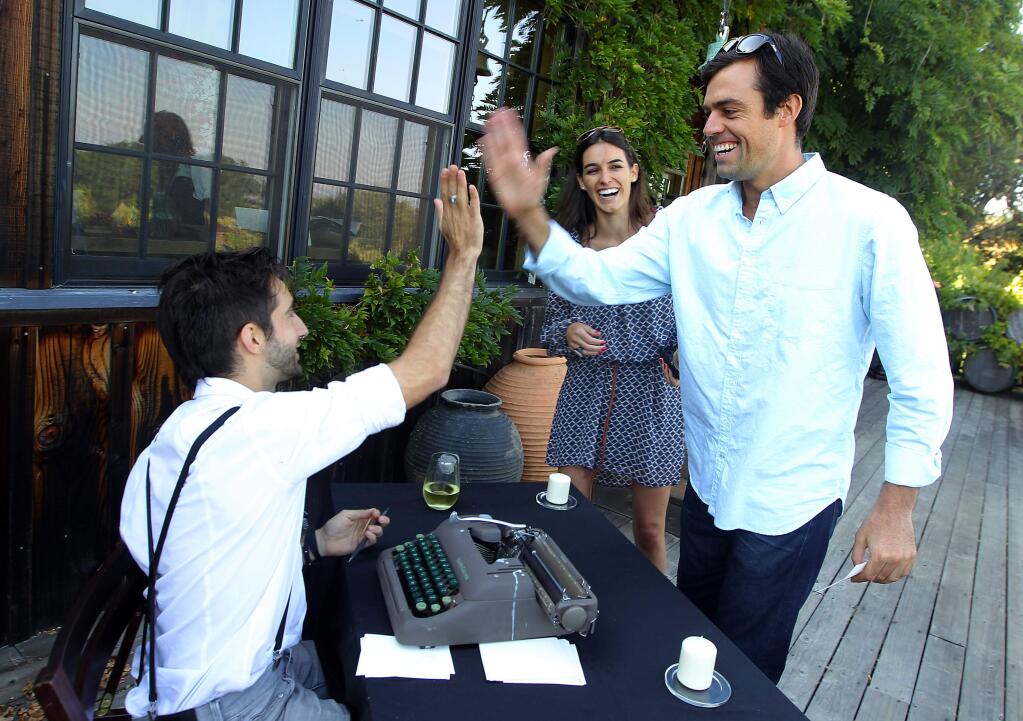 Mikey Samples high-fives Ryan Ashley after he composed a personalized 'Untouched Poetry' for Samples and K.K. Cressman at a fundraiser for the Turquoise Mountain Foundation at Stubbs Vineyard on Saturday, Aug. 2, 2014. (John Burgess / The Press Democrat)