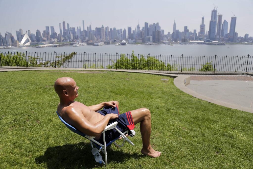 FILE - In this Tuesday, May 15, 2018 file photo, Rick Stewart sits in the sunshine with the New York City skyline in the background, in a park in Weehawken, N.J. According to weather records released on Wednesday, June 6, 2018, May reached a record 65.4 degrees in the continental United States, which is 5.2 degrees above the 20th century average. (AP Photo/Seth Wenig)