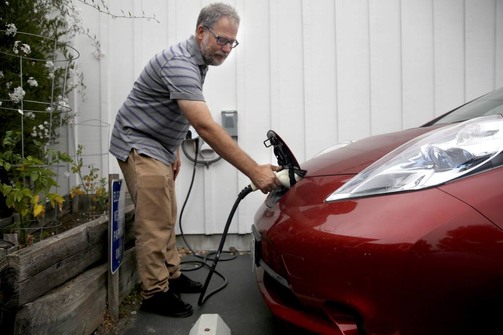Carl Mears unplugs the charger from his Nissan Leaf electric car at his condo complex before heading to work. Photo taken in Cotati, on Thursday, July 9, 2015. (BETH SCHLANKER/ The Press Democrat)