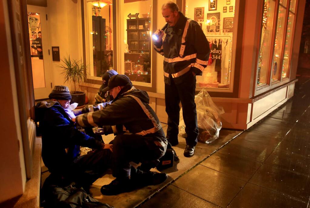Santa Rosa firefighters Chad Goff, Josh Gagnabin and Alan Simpson, right, evaluate the medical condition of a 56 year-old homeless man at Sixth and Davis Street in Santa Rosa, Wednesday Dec. 7, 2016. The man was taken to the hospital by ambulance. (Kent Porter / The Press Democrat) 2016