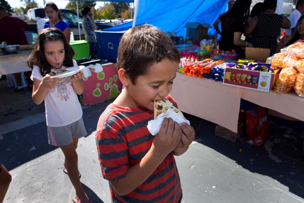 Nate Bourde, 6, and twin sister Roxy Bourde, both of Santa Rosa, enjoy quesadillas from the both 'Mi Texas Tacos' during the Roseland Community Festival in Santa Rosa on Sunday October 1, 2017. (Photo by Darryl Bush / For The Press Democrat)