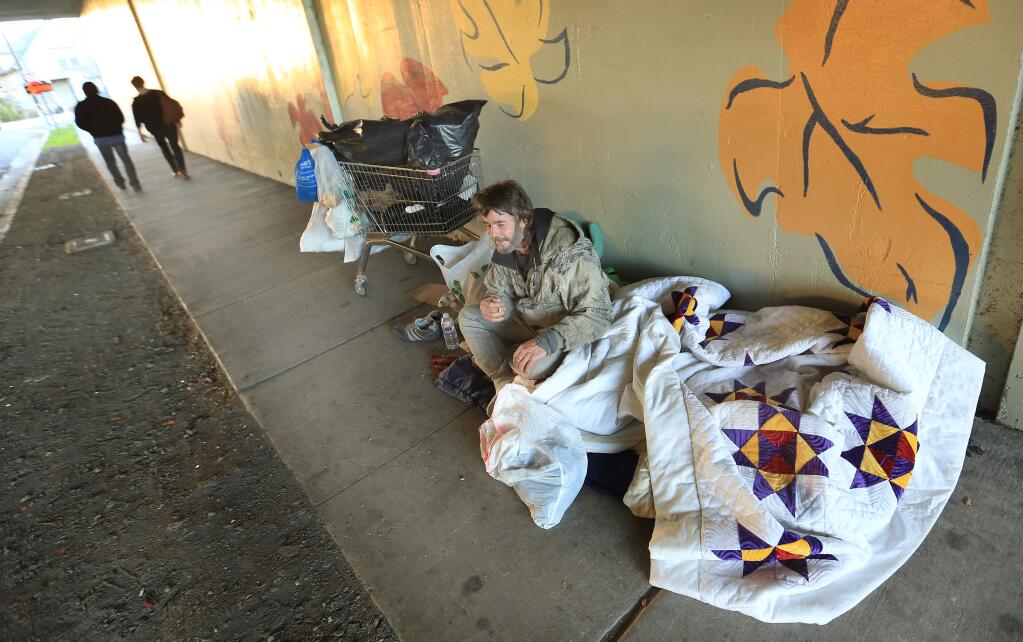 John woke Wednesday morning with two extra-heavy blankets over him given to him while he slept along Seventh Street in Santa Rosa. (KENT PORTER/ PD)