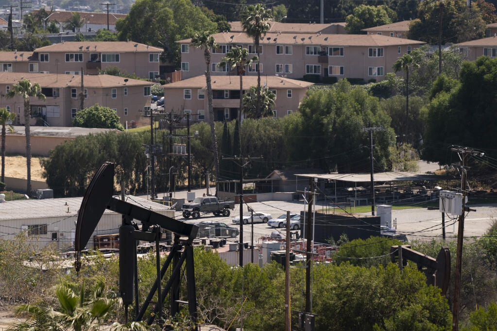 FILE - In this May 18, 2021, file photo, apartment buildings rise behind pump jacks operating at the Inglewood Oil Field in Los Angeles. California state oil regulators missed a spring deadline for new regulations designed to protect health and safety near oil and gas drillings sites. Environmental advocates have been pressuring Gov. Gavin Newsom's administration to adopt mandatory distances between wells and sites like schools and homes. (AP Photo/Jae C. Hong, File)