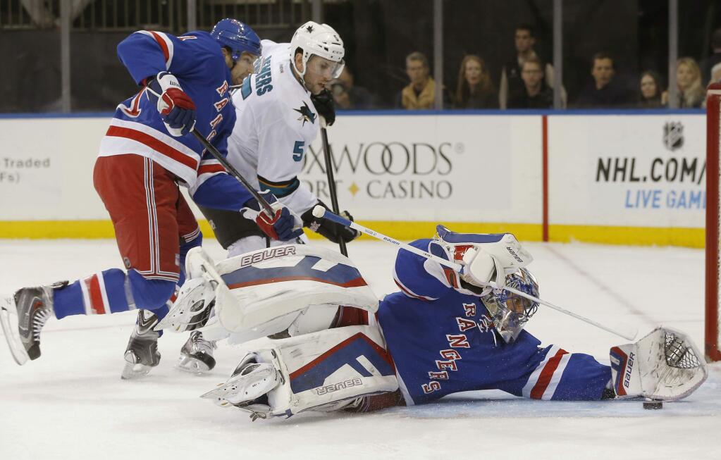 New York Rangers goalie Henrik Lundqvist (30), of Sweden, makes a save with San Jose Sharks defenseman Jason Demers (5) challenging and New York Rangers left wing Rick Nash defending during the first period of an NHL hockey game at Madison Square Garden in New York, Sunday, Oct. 19, 2014. (AP Photo/Kathy Willens)