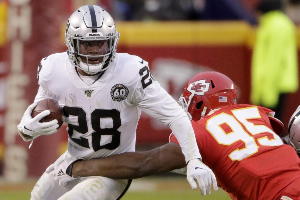 Oakland Raiders running back Josh Jacobs tries to break a tackle by Kansas City Chiefs defensive tackle Chris Jones during the first half in Kansas City, Mo., Sunday, Dec. 1, 2019. (AP Photo/Charlie Riedel)