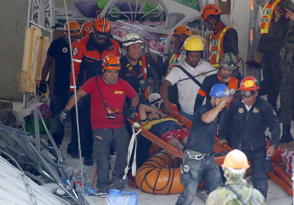 Rescuers carry an earthquake survivor after being pulled out from the rubble of a commercial building following a 6.1 magnitude earthquake in Porac township, Pampanga province, north of Manila, Philippines, Tuesday, April 23, 2019. The strong earthquake struck the northern Philippines Monday trapping some people in a collapsed building, damaged an airport terminal and knocked out power in at least one province, officials said. (AP Photo/Bullit Marquez)