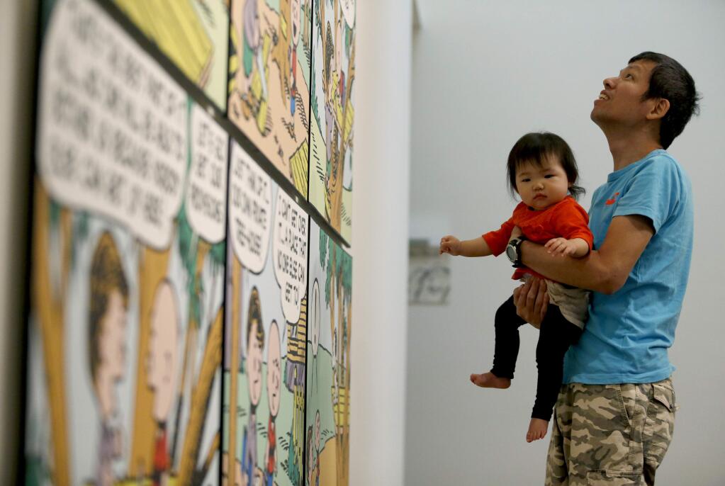 Yasutaka Yoshikawa, visiting from Japan, holds his 11-month-old daughter Sora as he looks at a Peanuts display at the Charles M. Schulz Museum on Monday, May 2, 2016 in Santa Rosa, California . (BETH SCHLANKER/ The Press Democrat)