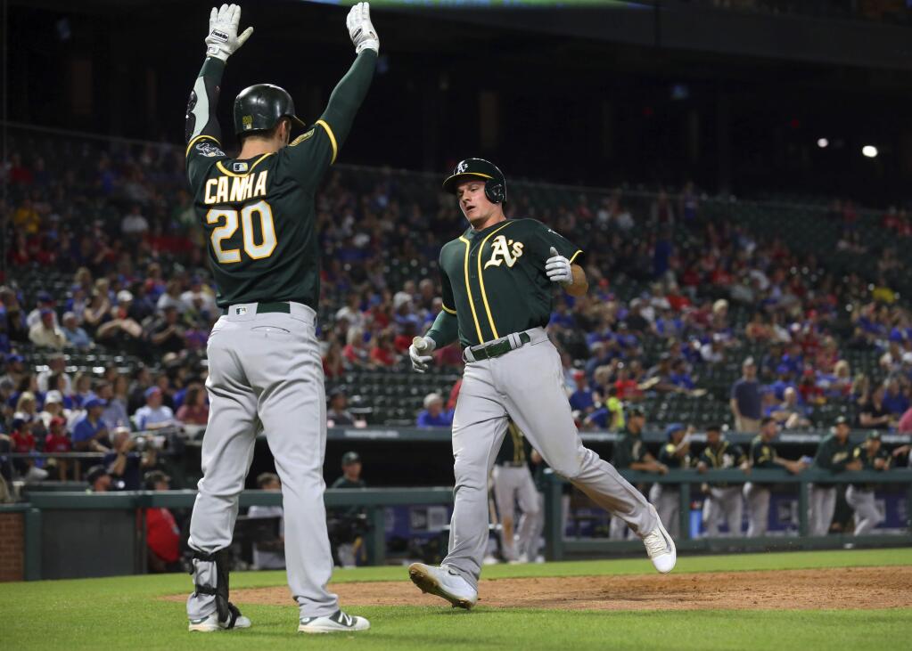 Oakland Athletics' Mark Canha signals to Matt Chapman as Champman crosses the plate, scoring on a double by Matt Olson in the eighth inning of a baseball game against the Texas Rangers on Tuesday, April 24, 2018, in Arlington, Texas. (AP Photo/Richard W. Rodriguez)