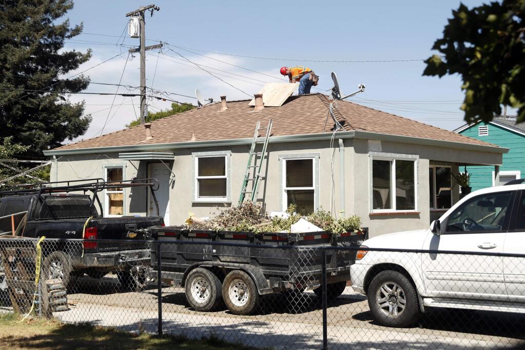 In this Aug. 5, 2018, picture, construction crews work at a house after a fire in Vallejo, Calif. Northern California police say a woman set herself on fire inside the home, killing herself and her twin 14-year-old daughters. (Scott Strazzante/San Francisco Chronicle via AP)