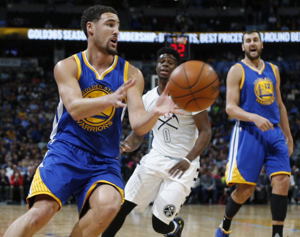Golden State Warriors guard Klay Thompson, front, fields pass as Denver Nuggets guard Emmanuel Mudiay, center, defends during the first half of an NBA basketball game Sunday, Nov. 22, 2015, in Denver. (AP Photo/David Zalubowski)