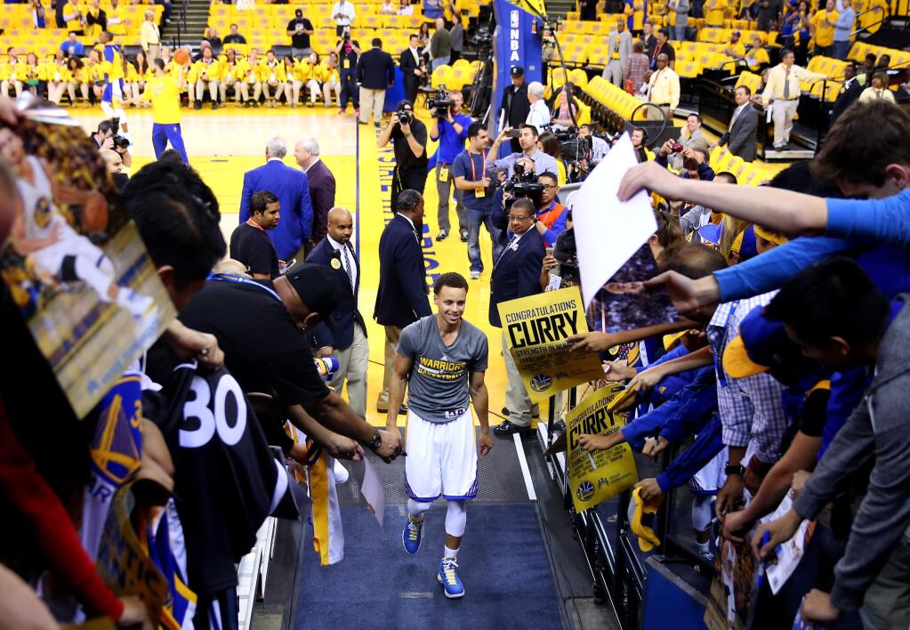Golden State Warriors guard Stephen Curry is greeted by fans after warming up before Game 2 of the NBA Playoffs Western Conference Semifinals at Oracle Arena, in Oakland on Tuesday, May 5, 2015. (Christopher Chung/ The Press Democrat)