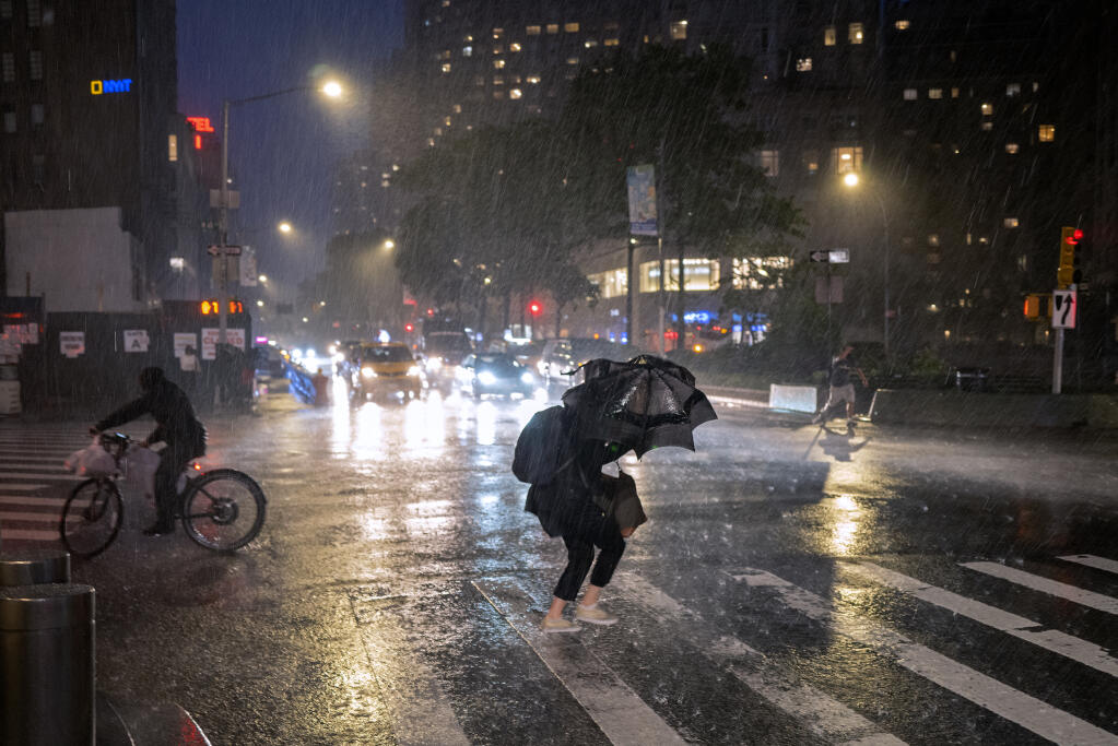 Pedestrians take cover near Columbus Circle in New York Wednesday, Sept. 1, 2021, as the remnants of Hurricane Ida remained powerful while moving along the Eastern seaboard. (AP Photo/Craig Ruttle)