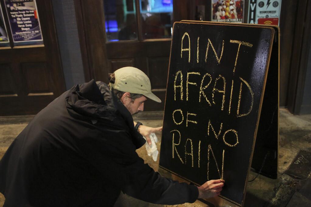 Nick Eberlein, bartender at The Merry Widow, draws a new sign as Tropical Storm Gordon arrives at night on Tuesday, Sept. 4, 2018 in Mobile, Ala. Tropical-force winds from fast-moving Gordon smashed into the coastline of Alabama and the western Florida Panhandle on Tuesday evening, the frontal edge of a system just offshore that forecasters warned could become a hurricane by the time it makes landfall. (AP Photo/Dan Anderson)