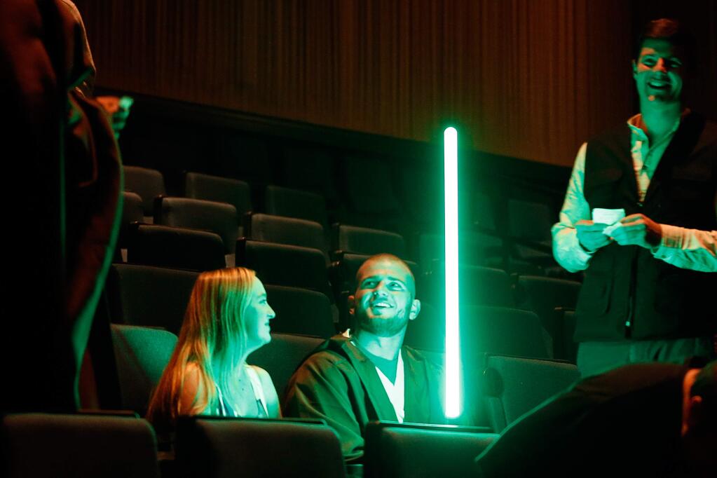 'Hey guys, we're sitting over here,' jokes Chad Gradek, center, of Windsor as he switches on his lightsaber while his friends find seats in the dimly lit theater before a preview showing of 'Star Wars: The Last Jedi' at the Roxy Stadium 14 movie theater in Santa Rosa, California on Thursday, December 14, 2017. (Alvin Jornada / The Press Democrat)