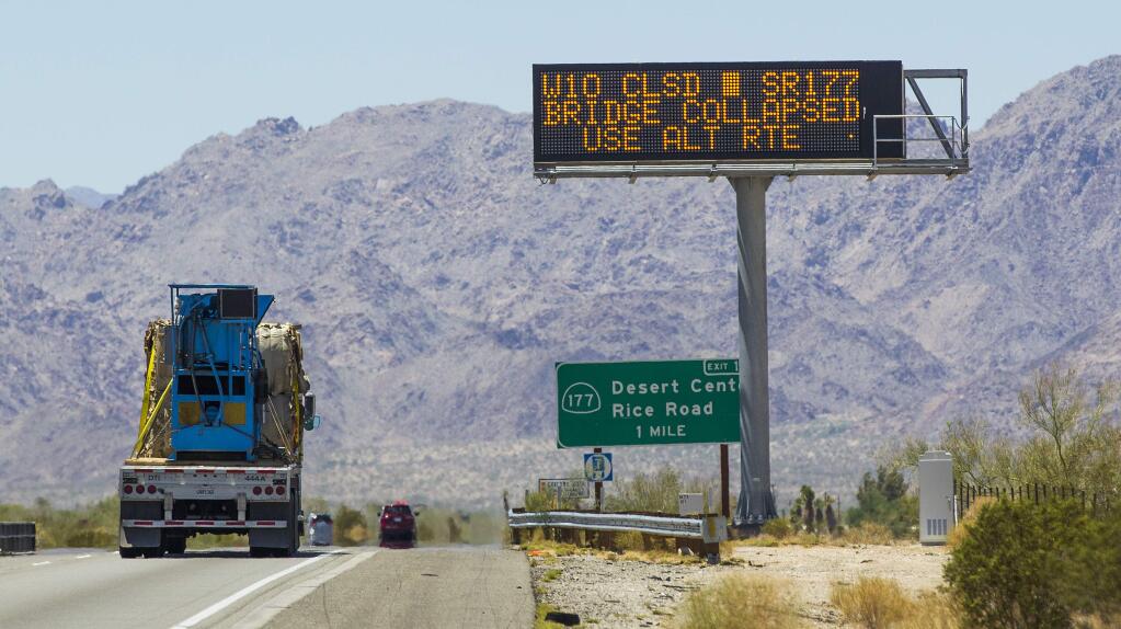 A vehicle passes a warning sign for a bridge collapse in the westbound lane of Interstate 10, Wednesday, July 22, 2015, near Blythe, Calif. Crews continued worked to fortify the bridge that a surge of floodwater damaged with a goal to reopen the main route connecting Los Angeles and Phoenix by Friday. (Tom Tingle/The Arizona Republic via AP)