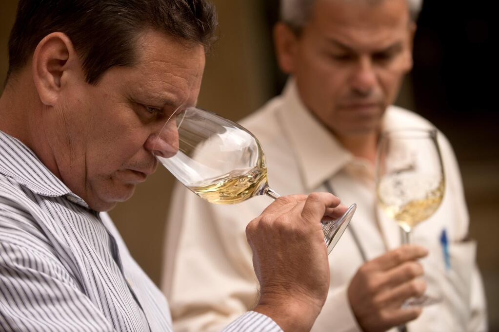 Orlando Blanco Blanco, left, maitre d' and sommelier of Floridita Restaurant takes in the aroma of a 2012 Qupé Estate Bottled Roussanne Bien Nacido Hillside Estate, Santa Maria Valley while Maitre d' Juan Jesus Machin Gonzalez of Presidente Hotel scruitinizes his glass during the Cuban Sommelier Summit at Ramekins in Sonoma, California, on July 21, 2014. (Alvin Jornada / For The Press Democrat)