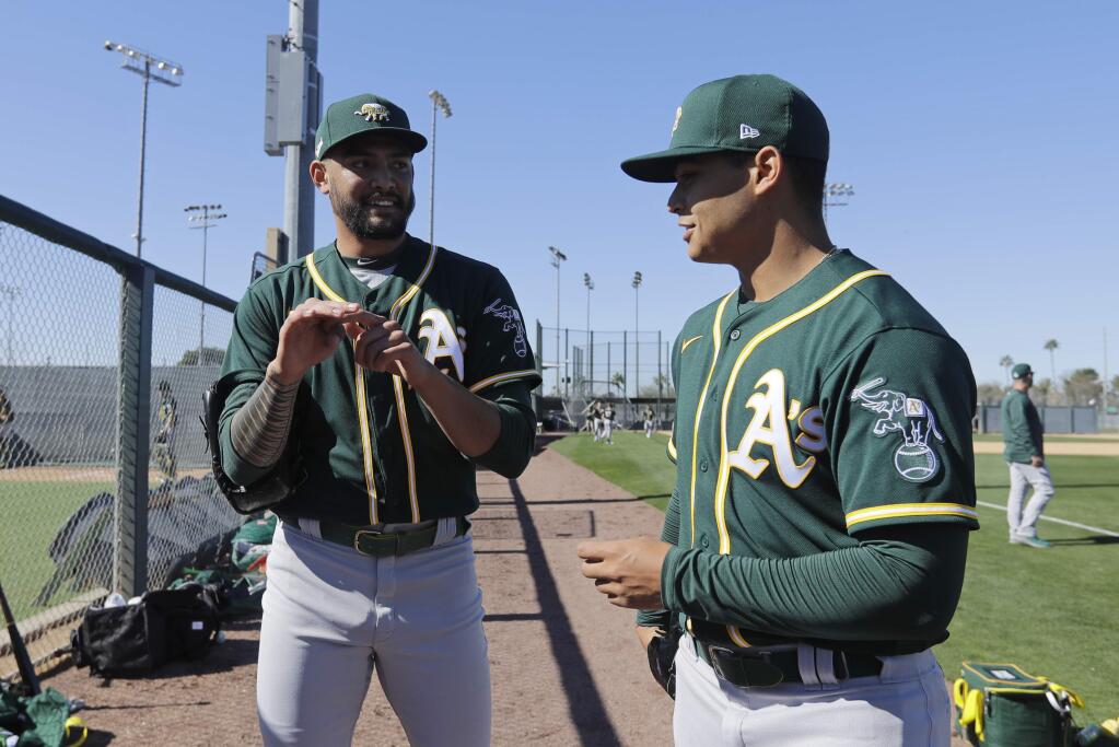 The Oakland Athletics' Sean Manaea, left, talks with Jesus Luzardo during spring training, Thursday, Feb. 13, 2020, in Mesa, Ariz. (AP Photo/Darron Cummings)