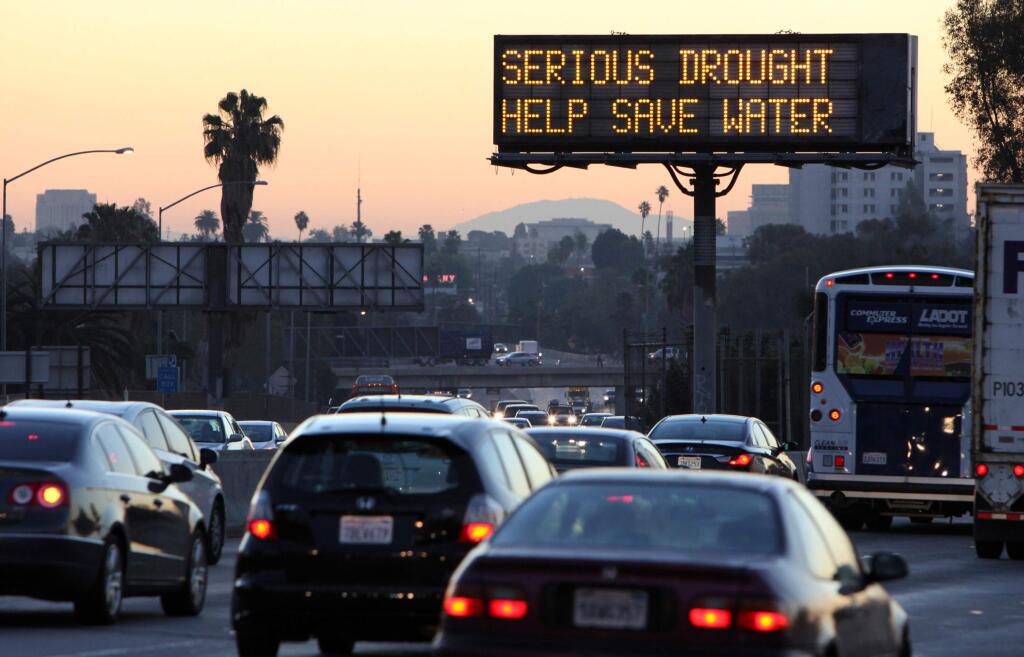 FILE - In this Feb. 14, 2014, file photo, morning traffic makes its way toward downtown Los Angeles along the Hollywood Freewaympast an electronic sign warning of severe drought. A plan to pump $1 billion of water spending into drought-stricken California cleared the Legislature on Thursday, March 26, 2015, and was sent to Gov. Jerry Brown, who is expected to sign the legislation. (AP Photo/Richard Vogel, File)